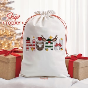 May include: A white Christmas gift bag with a red drawstring, featuring the name "NOAH" in festive, colorful lettering. The letters are decorated with holiday-themed designs, including stripes, reindeer antlers, and a Santa Claus face. Two wrapped gifts with red bows are in the foreground.