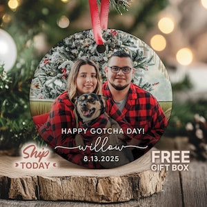 May include: Round Christmas ornament with a family photo, featuring a couple and a dog, wearing matching red and black plaid shirts. The ornament has the text "Happy Gotcha Day!" and the name "willow" with the date "8.13.2025". A red ribbon is attached for hanging.