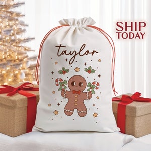 May include: White Christmas gift bag with a gingerbread person design and the name "taylor" printed on it.