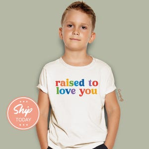 a young boy wearing a t - shirt that says raised to love you