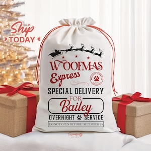 May include: A white canvas gift bag with a red drawstring, featuring the text "WOOFMAS Express" and "Special Delivery for Bailey." The design includes a Santa sleigh with reindeer and a paw print logo, perfect for pet gifts.