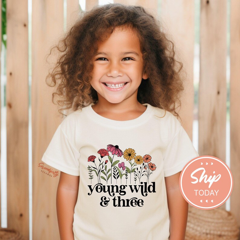 a young girl wearing a t - shirt that says young wild and three