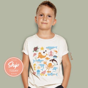 a young boy wearing a t - shirt with sea animals on it