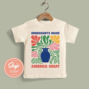 May include: Cream-colored toddler t-shirt with the text "IMMIGRANTS MAKE AMERICA GREAT" above a floral design in red, pink, yellow, and green. The design features a blue vase filled with flowers and foliage.