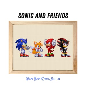 May include: Cross-stitch of Sonic the Hedgehog and friends: Tails, Knuckles, and Shadow. The characters are in pixelated form, with bright colours. The text "SONIC AND FRIENDS" is above the characters, and "BAM BAM CROSS STITCH" is below.