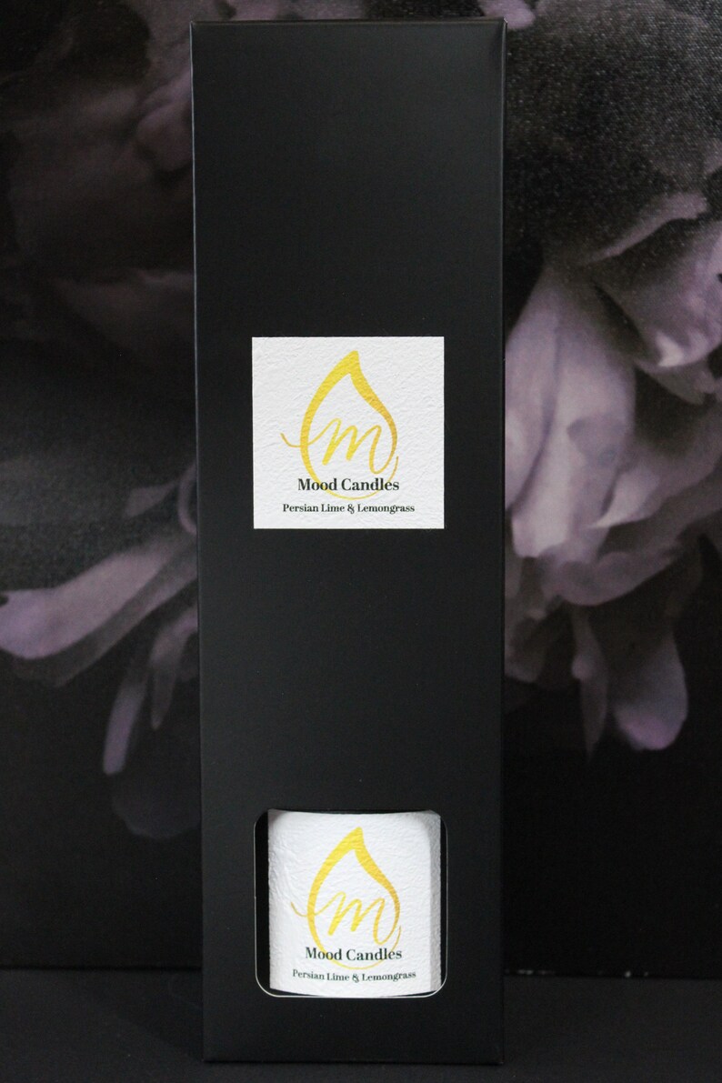 May include: A black box with a white label that says "Mood Candles" and "Persian Lime & Lemongrass". The box is sitting on a purple and white floral background.