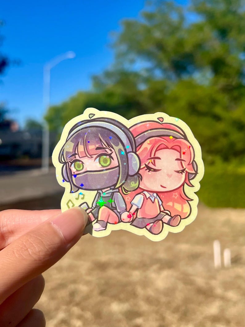 May include: A vibrant sticker depicting two anime-style figures holding hands. One character has black hair and a face covering, the other has pink hair. Both are wearing headphones and seated. The sticker has a yellow border.