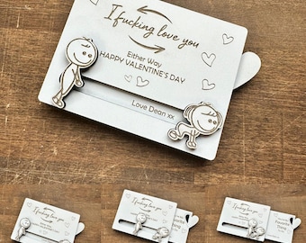 May include: A white Valentine's Day card with the text "I fucking love you" and "Happy Valentine's Day." The card features two cartoon figures and a sliding mechanism revealing "You're my favorite thing to do."