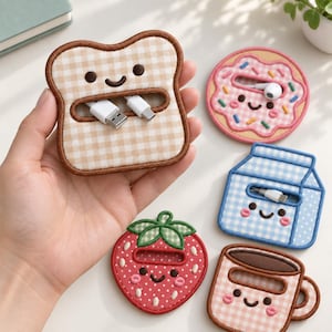 以下が含まれることがあります： かわいい顔が刺繍された5種類のケーブルオーガナイザー。ベージュのギンガムチェックのトースト、スプリンクル付きのピンクのドーナツ、青いギンガムチェックの牛乳パック、赤いイチゴ、持ち手付きのベージュのギンガムチェックのコーヒーマグの形をしています。