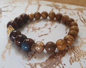 May include: A brown and beige beaded bracelet with gold accents. The bracelet has a mix of round and textured beads.