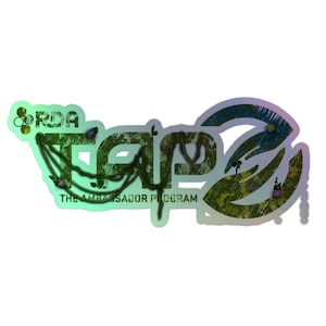 May include: A sticker featuring the text RDA TAP3 THE AMBASSADOR PROGRAM in a stylised font. The design incorporates a green and iridescent gradient with a textured, forest-like pattern and thin, dark green vine-like lines draped across the letters.