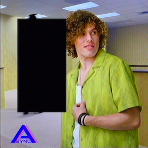 Curly-haired model wearing the yellow Backrooms Level 0 wallpaper camp shirt in an office hallway