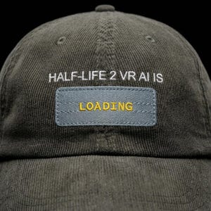 Könnte beinhalten: Dunkelgrüne Cord-Baseballkappe mit dem weißen Schriftzug "HALF-LIFE 2 VR AI IS" über einem rechteckigen Aufnäher. Der Aufnäher trägt die gelbe Aufschrift "LOADING".