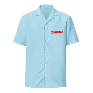 May include: A pale blue short-sleeved shirt with a button-down front and a classic collar. The shirt has the red letters "SDN" printed on the left chest. Made from a lightweight material, this shirt is ideal for warmer weather.
