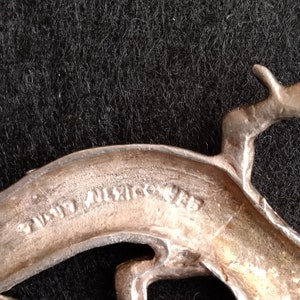 Op de afbeelding: Zilverkleurige metalen broche met een gestileerd springend hert. De achterkant van de broche is gemarkeerd met "Hand Wrought."