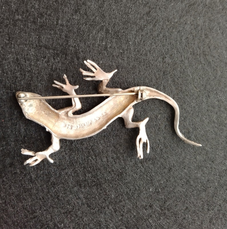 Op de afbeelding: Zilveren hagedis broche met een gedetailleerd ontwerp en een pin aan de achterkant. De broche is gemarkeerd met "Sterling Silver".