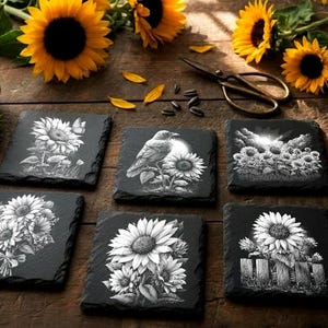 May include: A collection of six black slate coasters with white sunflower designs. Fresh sunflowers, scissors, and a ball of twine are arranged on a wooden surface, creating a rustic, floral theme.