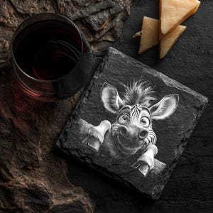May include: A black slate coaster with a whimsical zebra illustration. The zebra is peering over a wooden ledge. A glass of red wine and cheese wedges are also present.