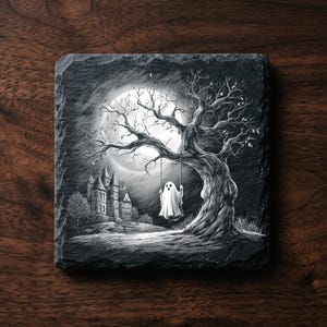 May include: A square slate coaster featuring a black and white illustration of a ghost sitting on a swing hanging from a gnarled tree. In the background, a large full moon illuminates a castle with multiple towers under a dark, cloudy night sky.