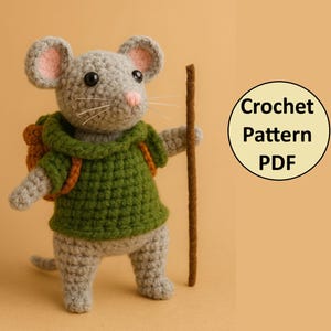 May include: A crocheted mouse figure with grey fur, pink ears, and a pink nose. It wears a green hooded shirt and a brown backpack, holding a brown stick. The image includes a circular graphic that reads "Crochet Pattern PDF".