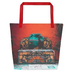 May include: A large tote bag with a vibrant design featuring a red handle and a colorful image of a bench against an orange wall. The bench has a detailed mosaic design with a landscape scene.