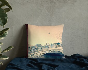 May include: A throw pillow with a vintage-style image of a bridge over a river in a city. The bridge is white and the city buildings are in the background. The pillow has a maroon border.