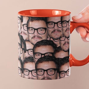 May include: A red and white ceramic coffee mug with a pattern of multiple faces wearing glasses. The mug has a red handle.