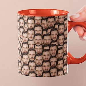 Może przedstawiać: Czerwony kubek do kawy z białym wnętrzem i czerwonym uchwytem. Kubek jest pokryty wzorem powtarzających się obrazów twarzy mężczyzny.