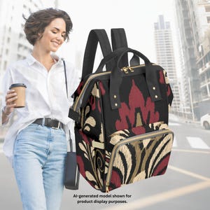 May include: A black backpack featuring a bold, repeating damask-style pattern in deep red and beige. The bag includes a top handle, adjustable shoulder straps, gold-tone zippers, and a front zippered pocket. Text at the bottom reads: AI-generated model shown for product display purposes.
