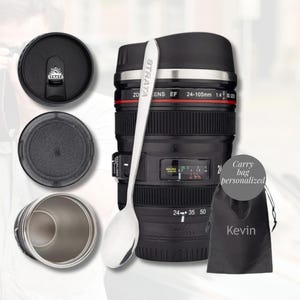 May include: A black and silver travel mug designed to resemble a camera lens, with the text "STRATA" on a silver spoon. Includes a black lid, a silver interior, and a personalized carry bag with the name "Kevin".