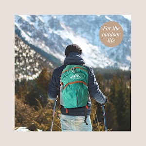 May include: A person wearing a dark blue jacket and light blue jeans, carrying a teal backpack with orange accents, hiking in a snowy mountain landscape. The backpack has a mountain logo and the text "For the outdoor life".