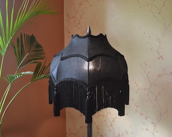 May include: A black lampshade with a fringe trim. The lampshade is made of fabric and has a classic design.