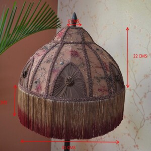 Op de afbeelding: Een bruine en beige lampenkap met een franje rand. De lampenkap is 22 cm hoog en 41 cm breed. De bovenkant van de lampenkap is 6 cm breed.