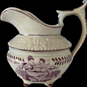 Könnte beinhalten: Eine weiße Keramikkanne mit braunem Henkel und einem braunen und weißen Design. Das Design zeigt zwei Kinder in einer spielerischen Szene.