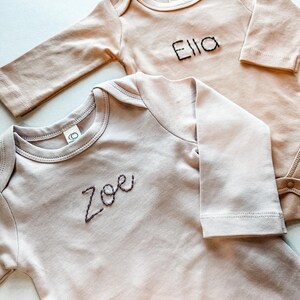 Two Colored Organics Long Sleeve Bodysuits with the names Zoe and Ella Hand Stitched.