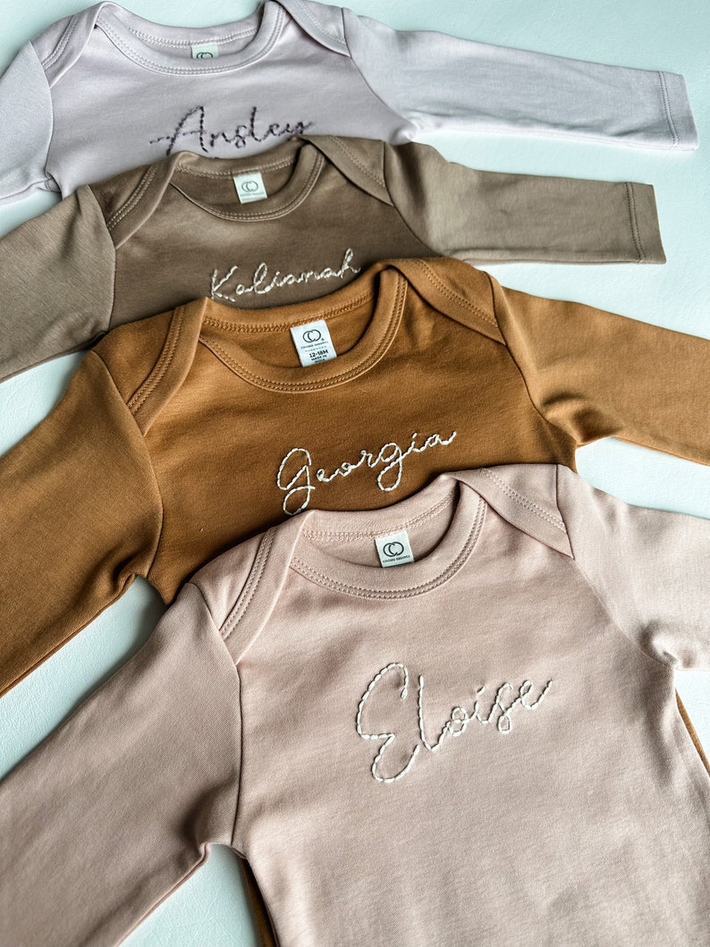 Hand Embroidered long sleeve baby onesies with names hand embroidered across the chest.