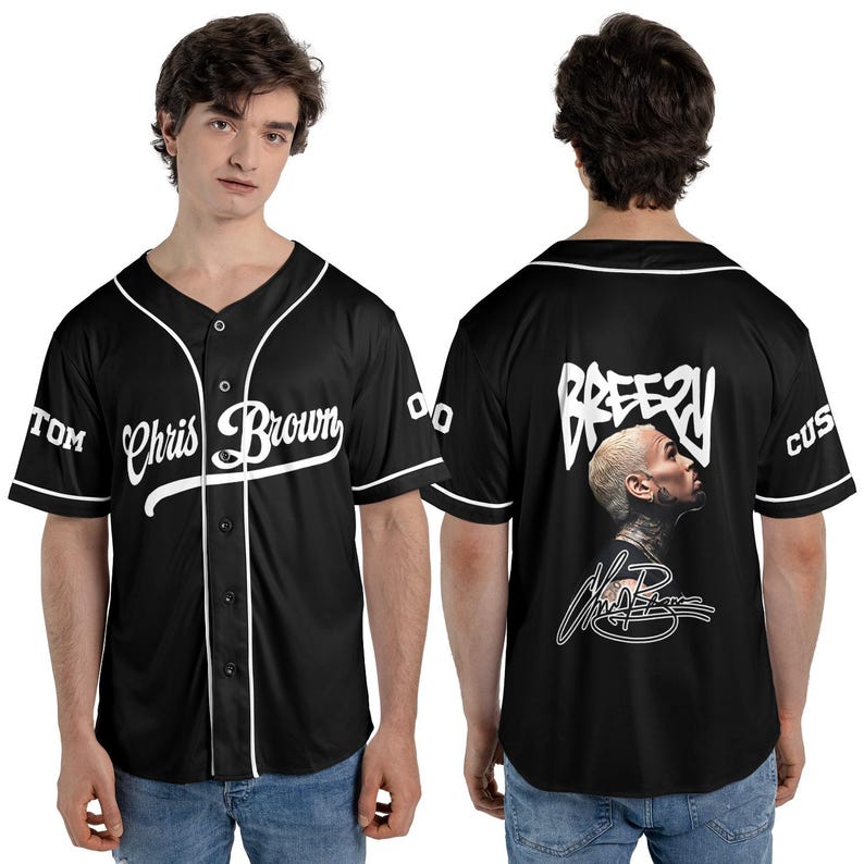 May include: Black baseball jersey with white trim and the name "Chris Brown" in script across the front. The back features the word "Breezy" above a portrait and signature. Sleeves have "TOM" and "CUS" text.