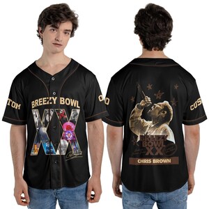 May include: Black baseball jersey with brown trim and buttons. The front features the text "Breezy Bowl XX" with a collage of images and a signature. The back displays a sepia-toned image of a singer and the text "Chris Brown".