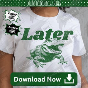 May include: A white short-sleeved t-shirt featuring a green graphic of an alligator with its mouth open. Above the alligator, the word "Later" is printed in a bold, distressed green font. The design includes a textured, vintage-style finish.