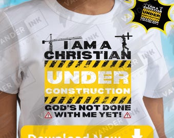 May include: A white t-shirt featuring a graphic design with a construction crane and a silhouette of a person carrying a cross. The text reads I AM A CHRISTIAN UNDER CONSTRUCTION GOD'S NOT DONE WITH ME YET! with yellow and black hazard stripes.