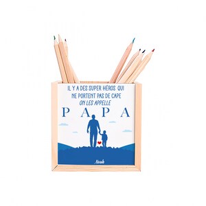 Peut inclure: Pot à crayons en bois avec un design bleu et blanc. Il affiche le mot "PAPA" et le texte "IL Y A DES SUPER HÉROS QUI NE PORTENT PAS DE CAPE ON LES APPELLE". Contient des crayons de couleur.