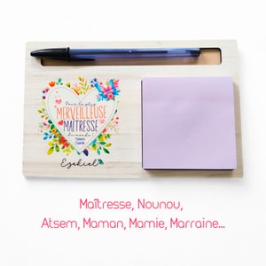 Peut inclure: Organisateur de bureau en bois avec un bloc-notes adhésif rose, un porte-stylo et un cœur décoratif avec le texte "Pour la plus MERVEILLEUSE MAITRESSE du monde Madame Duardn Ezekiel".