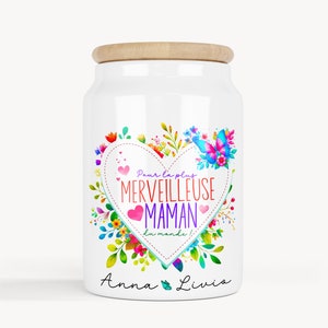 Peut inclure: Pot en céramique blanche avec un couvercle en bois. Le pot est décoré d'un cœur coloré avec le texte "Pour la plus merveilleuse maman du monde!" et les noms "Anna & Livio".