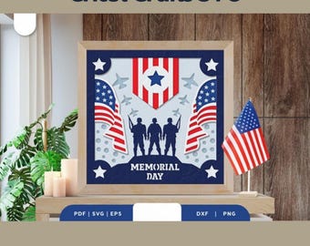 May include: A framed papercraft design featuring three silhouetted soldiers standing on a hill with the words "Memorial Day" below them. The design is surrounded by stars and American flags.