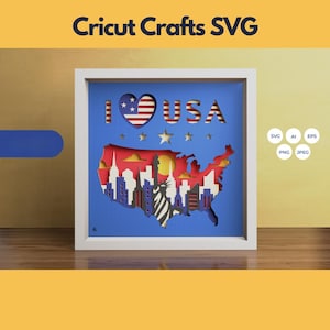 Puede incluir: Un marco blanco con fondo azul y un diseño de corte de papel de los Estados Unidos con las palabras "I LOVE USA" y un corazón con el diseño de la bandera estadounidense.