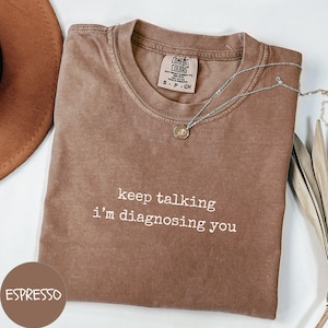 May include: A brown t-shirt with the text "keep talking i'm diagnosing you" in white. The shirt is made of a soft, comfortable material and has a relaxed fit.