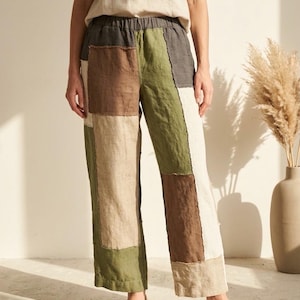 Op de afbeelding: Patchwork linnen broek in bruin-, groen- en beigetinten. De broek heeft een wijd model en een comfortabele elastische tailleband. Het model draagt een bijpassend beige linnen T-shirt en geweven espadrilles.