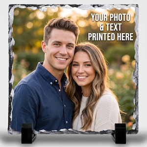 May include: A square slate plaque with rough, chiseled edges featuring a printed photograph of a smiling couple. The text "YOUR PHOTO & TEXT PRINTED HERE" is displayed in white capital letters in the upper right corner. Two black stands support the base.
