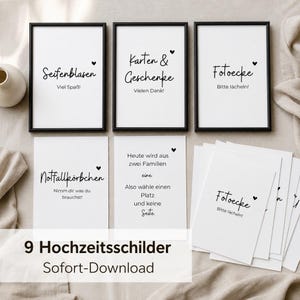 Op de afbeelding: Een set van negen witte rechthoekige trouwbordjes met zwarte tekst en kleine hartjesiconen. Drie bordjes worden getoond in zwarte lijsten, terwijl andere los liggen. De tekst bevat Duitse zinnen zoals Seifenblasen, Karten & Geschenke en Fotoecke.