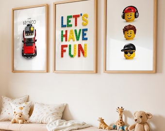 May include: Three framed prints with wooden frames hang on a white wall. One print features a red Ford Bronco toy, another says "LET'S HAVE FUN" in colorful block letters, and the third shows Lego heads. A wooden bench with storage drawers is below.